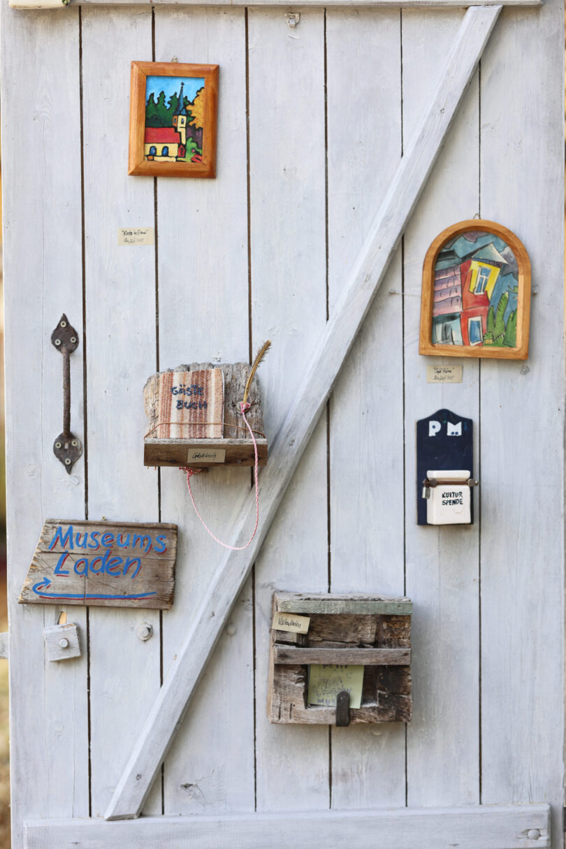 Blick auf die hölzerne Eingangstür mit kleinen Kunstwerken des Miniatur-Kunstmuseums in Elend, das die Werke des Künstlers Bafuß, bürgerlich Jochen Tiemann, zeigt. Auch ein Gästebuch ist installiert.