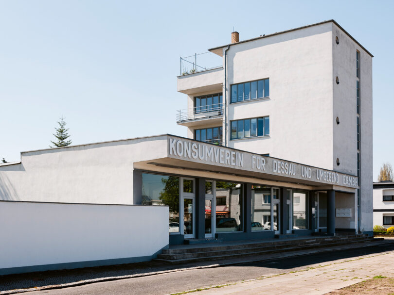 Ein weißes Bauhaus-Gebäude mit dem Schriftzug „Konsumverein für Dessau“