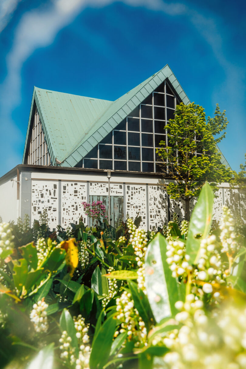 Die Markuskirche in Essen, ein Spielort der Manifesta, davor blühen Maiglöckchen