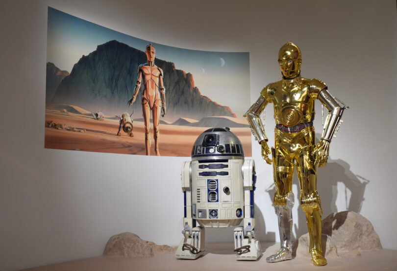 Der Roboter R2-D2 des Produktionsdesigners Norman Reynolds (l) und das Kostüm von John Mollo für die Figur C-3PO aus der „Star Wars“-Reihe
