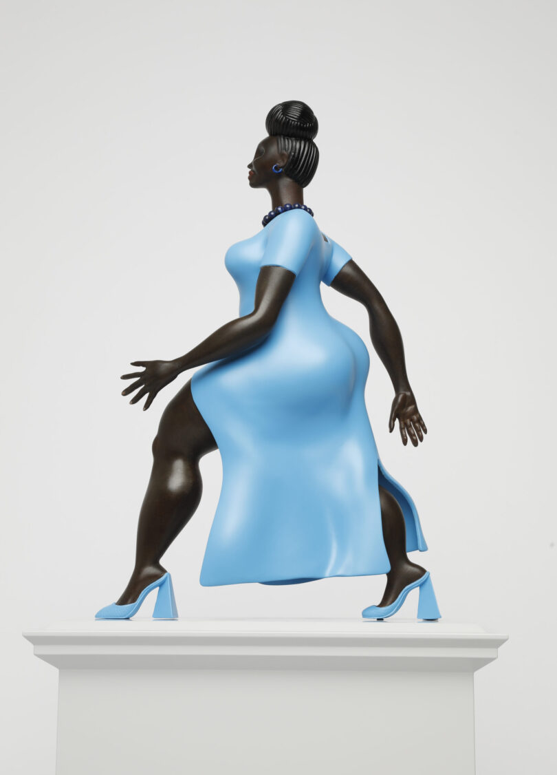 Seitenansicht einer Skulptur, welche eine gehende schwarze Frau in blauem Kleid verkörpert