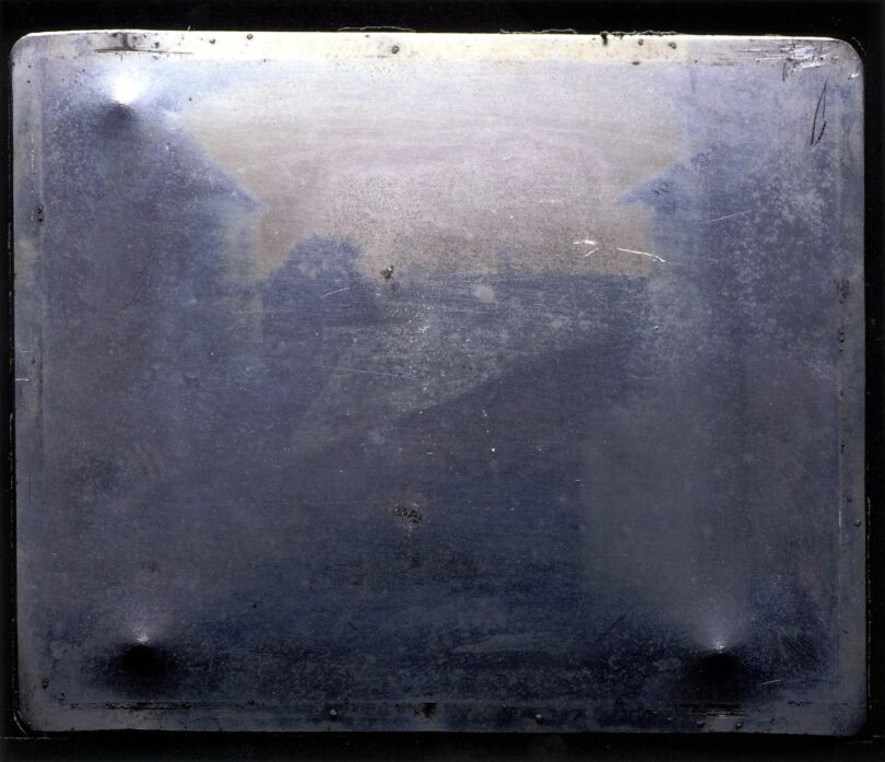Die erste erhaltene Fotografie lässt wenig blicken, das verschwommen graue Bild deutet den Blick aus einem Fenster heraus nur an.
